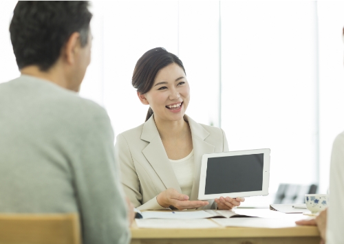 女性がタブレットを見せながら男性と話している