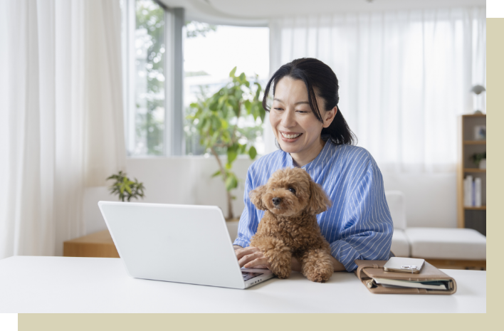 女性が犬を抱きながらパソコンを触っている